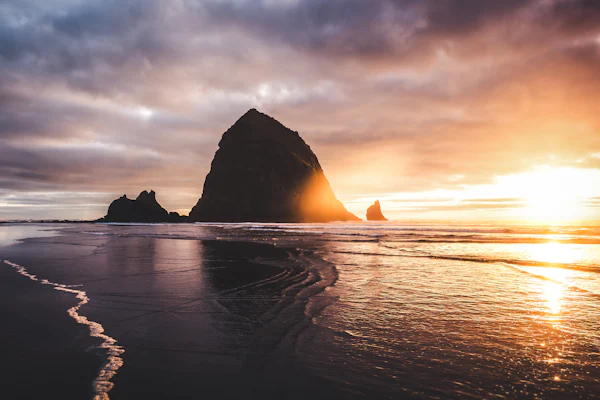 Haystack Rock on the wet sand at Cannon Beach at golden hour