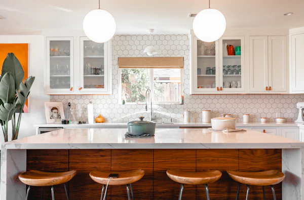 White kitchen with four wood stools at the counter and open shelves