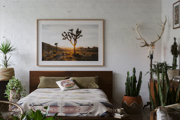 Bedroom with a king bed, cactus plants, and a Joshua tree print above the headboard
