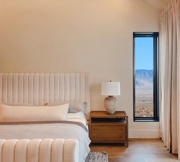 Calm bedroom with a queen bed and a tall window framing the desert