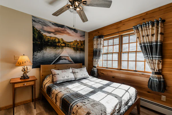 Bedroom with a queen bed in plaid quilts beside a wide window
